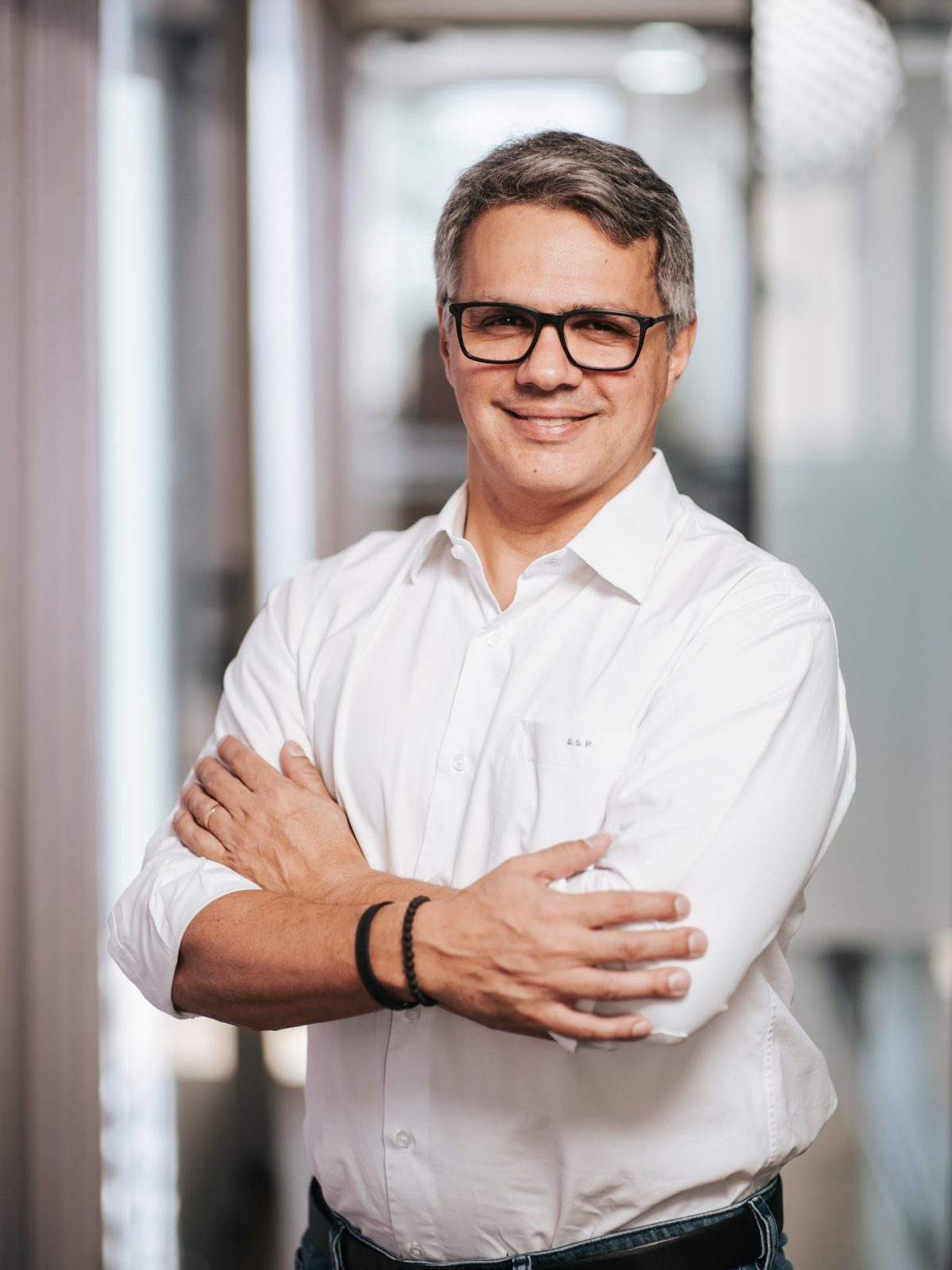 Retrato corporativo de homem de camisa branca e óculos, de braços cruzados