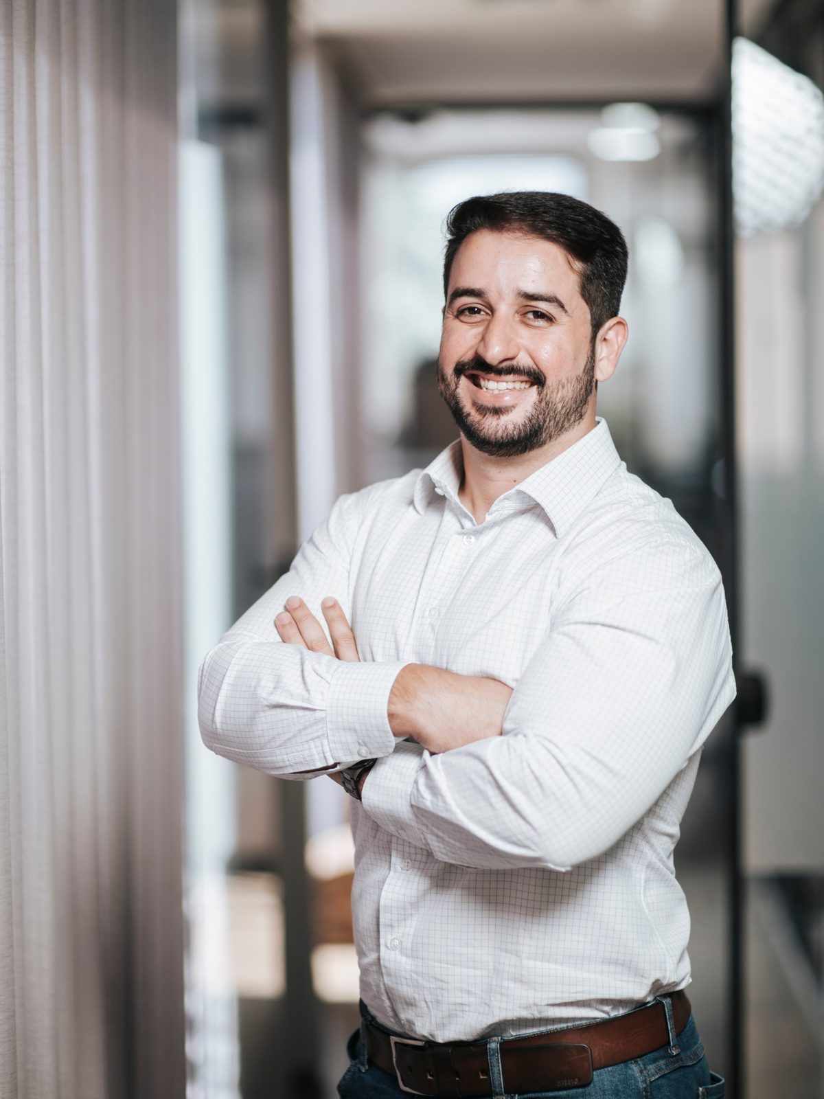 Retrato corporativo de homem de barba sorrindo, de braços cruzados
